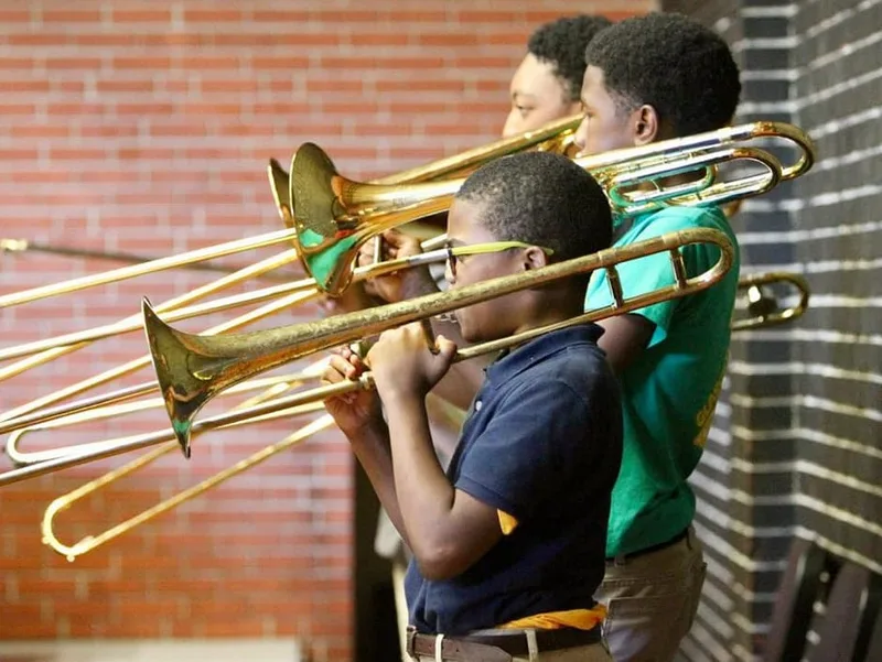 Three students playing trombones. 