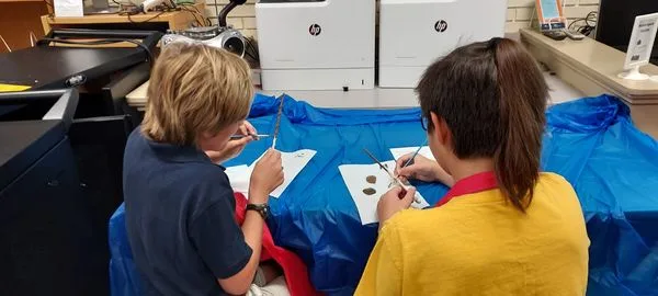 Two students working on  an art project (painting wands). 