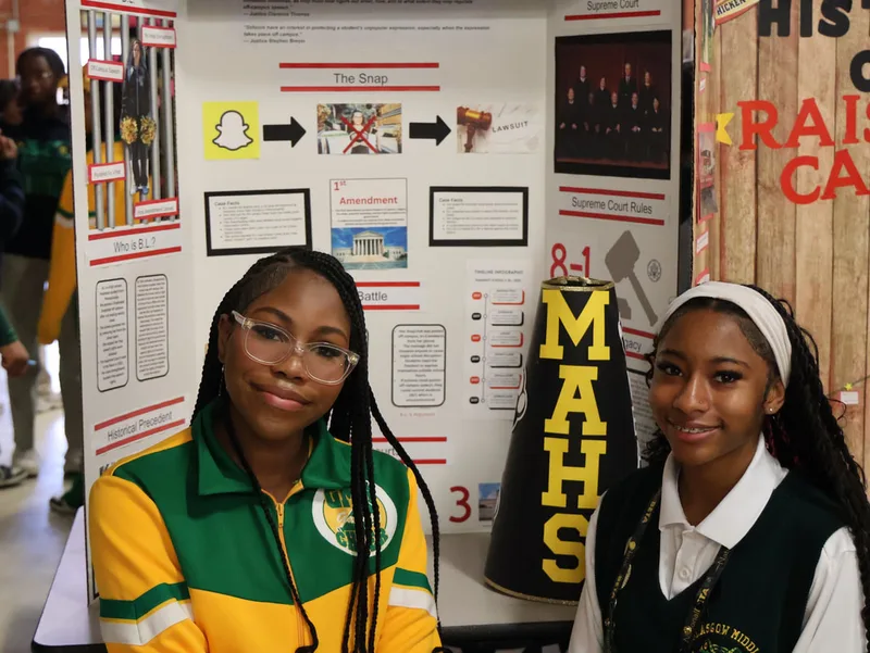 Two students posing by a project board about First Amendment and Supreme Court case.
