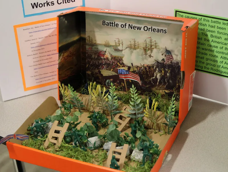 Shoebox diorama of the Battle of New Orleans with toy soldiers, plants, and flags.
