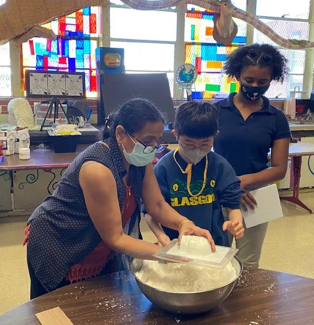 A teacher assisting two students with a sugar skull molding project.
