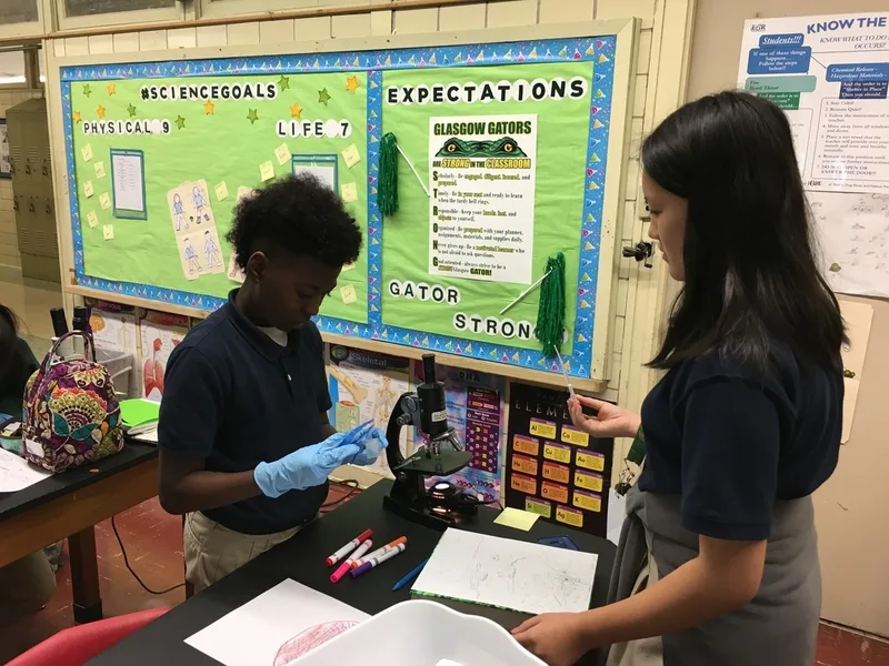A male student and a female students are working with a microscope.