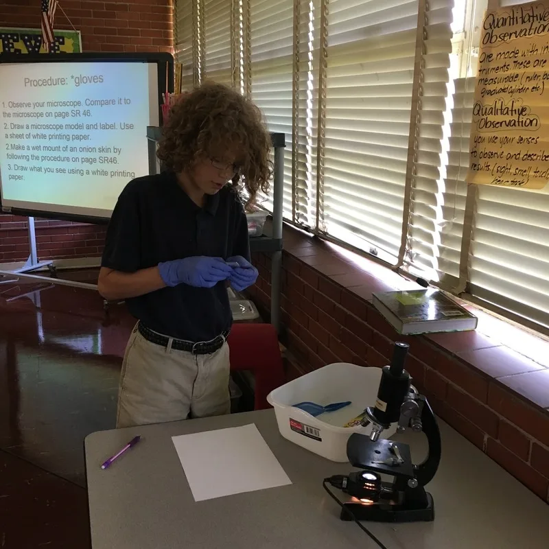A male student is preparing a slide to examine with a microscope.