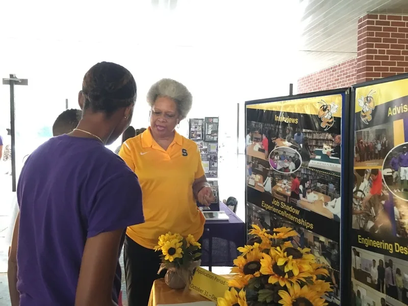 A student and a parent speak with a representative from a local high school. 