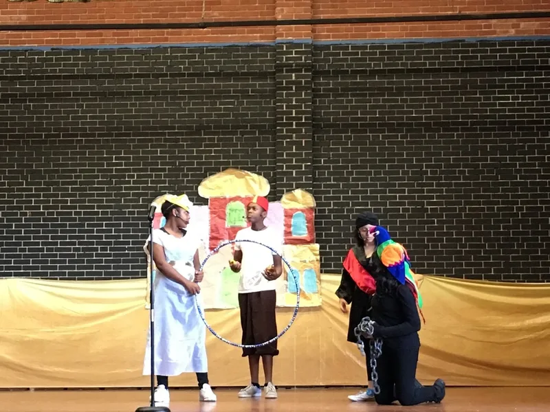 A boy dressed as Aladdin is speaking to three students.