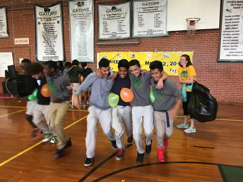 A group of male students walking in a line. They are carrying balloons. 